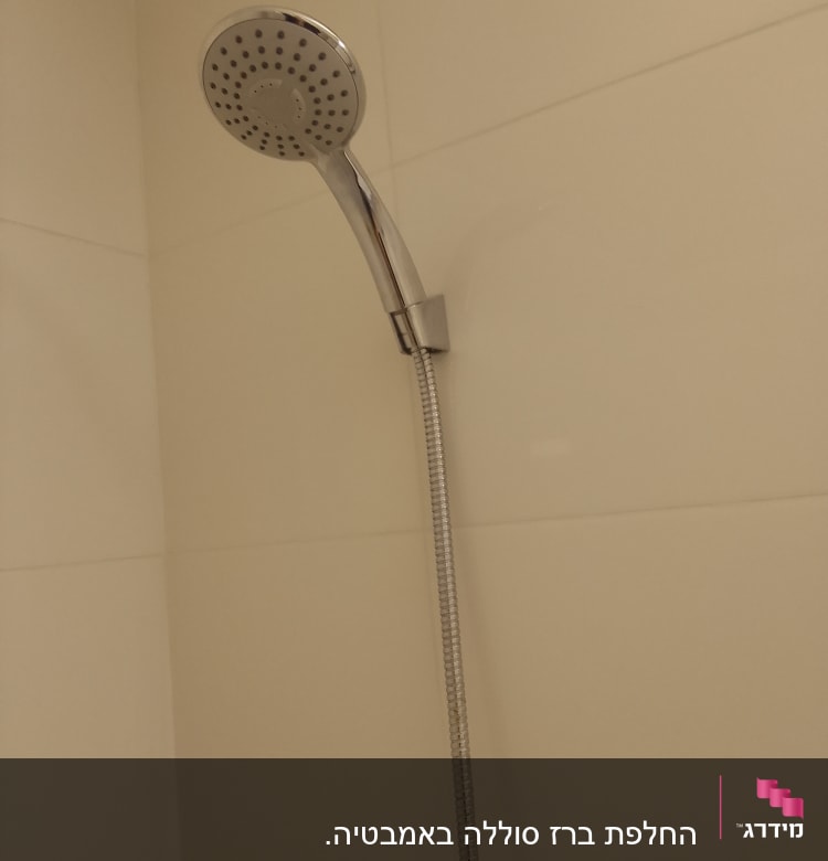 ראש מקלחת מתכת מחובר לקיר בחדר אמבטיה